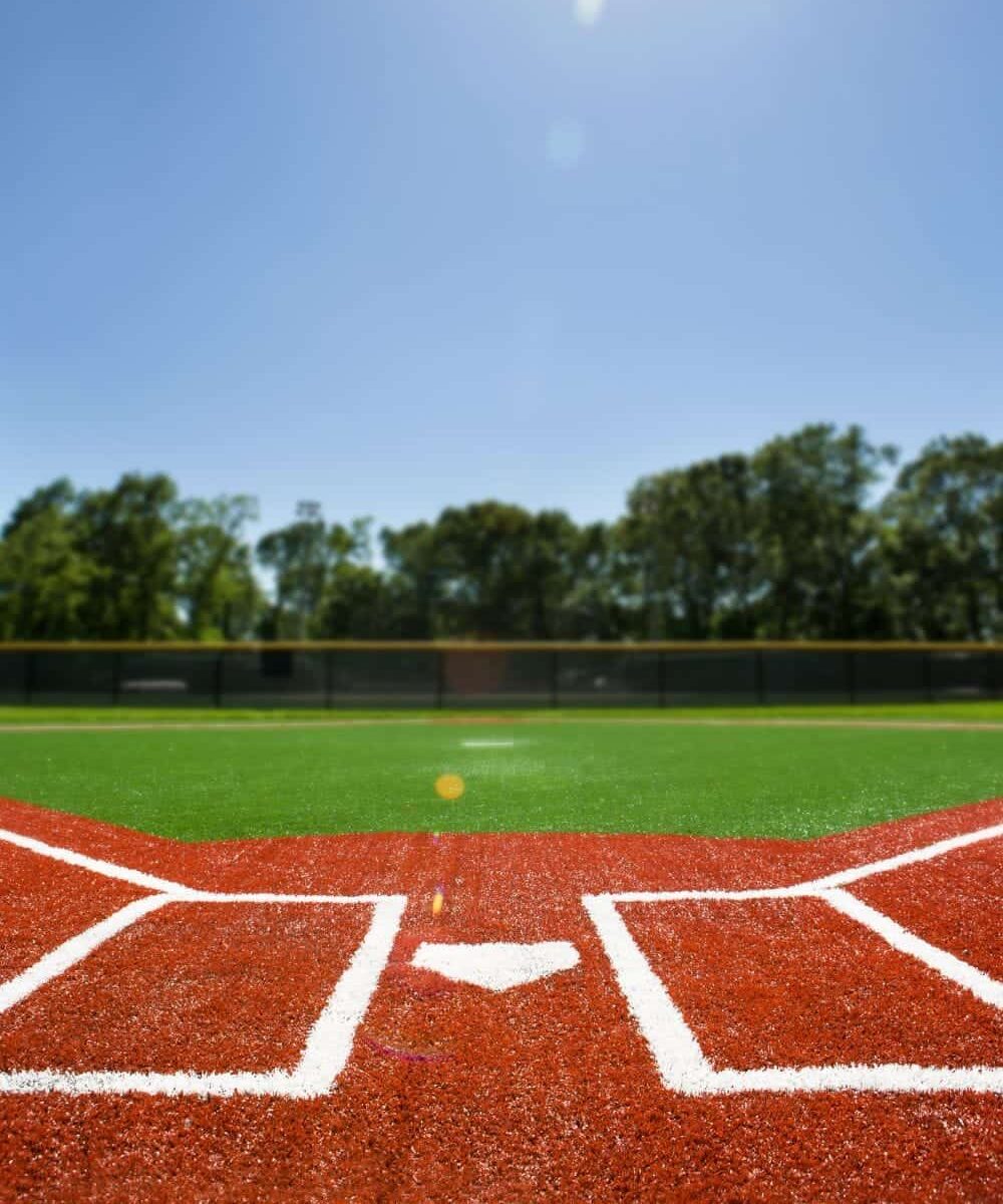 picture of a baseball home plate done in synthetic turf. Red turf with white lines for the home plate and base paths, and green turf for the outfield.