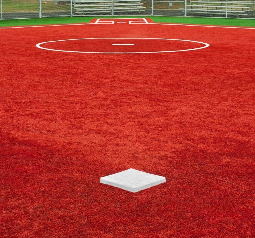 baseball field looking from 2nd base back to home plate. Bright red artificial turf turf on the entire infield, mound, and base paths. Green artificial grass in foul territory