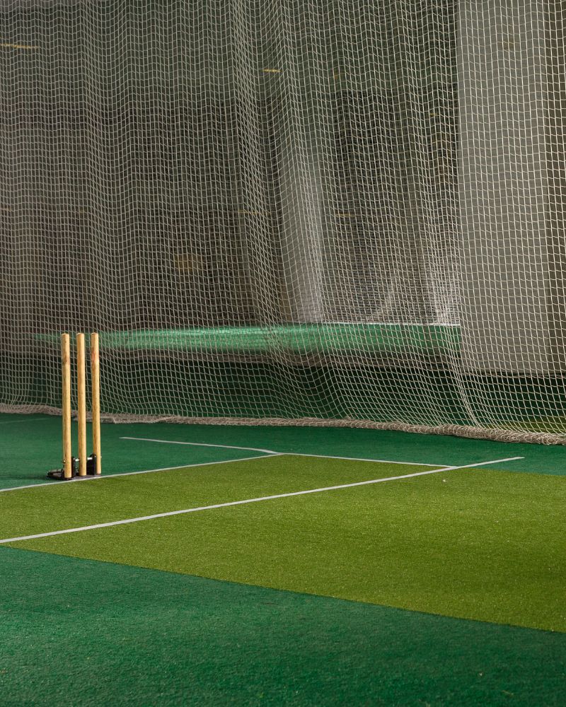 picture of indoor cricket artificial grass with cricket wickets and a net