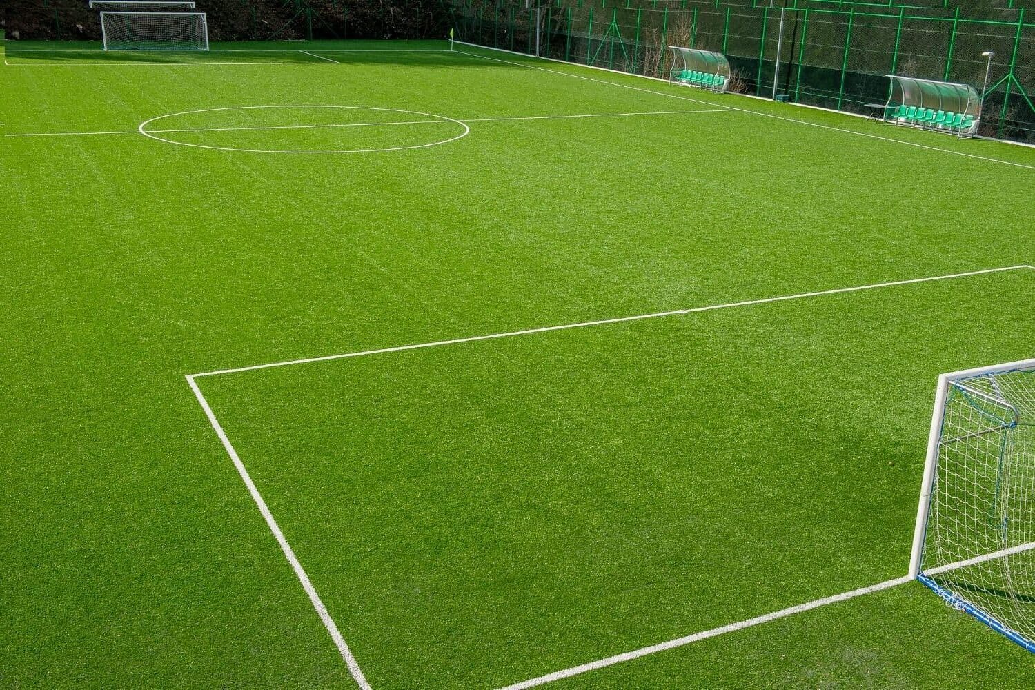 picture of an artificial grass soccer field installation. Big white soccer goal at one end of the field.